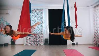 空中瑜伽-两个女人躺在<strong>吊床</strong>上，在<strong>吊床</strong>上摆动-互相看着对方